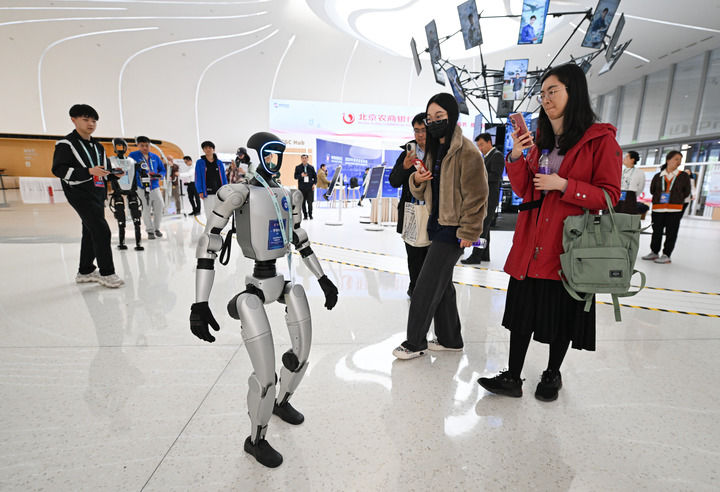 2025年3月26日，北京中关村国际创新中心的一款正在行走的宇树G1机器人吸引人们拍照留影。新华社记者 陈钟昊 摄.jpg