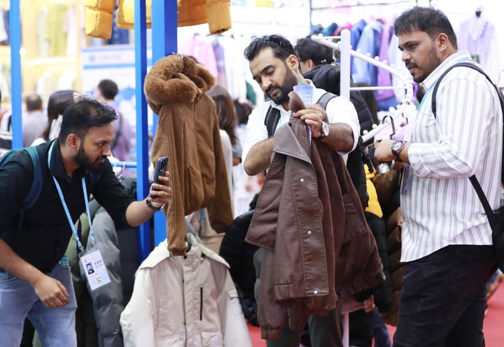 2025年5月1日，在广州开幕的第137届广交会第三期上，境外采购商在一家服装企业的展区拍摄样品。新华社记者 王瑞平 摄.jpg