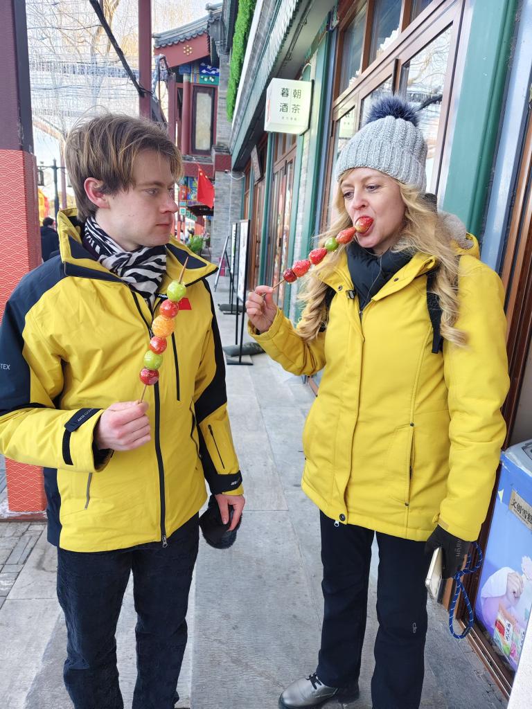 德国游客乌尔丽克与埃米尔在什刹海吃糖葫芦。新华社记者 于佳欣 摄  .jpg